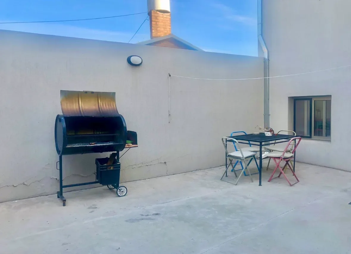 Patio del complejo con chulengo, mesa y sillas